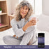 Woman in pajamas relaxes with a mug beside a Melatonin + Magnesium Glycinate bottle.