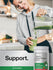 A young woman pours a green smoothie from a blender into a glass, next to a jar of Organic Super Greens Powder.
