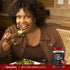 A woman enjoying a salad next to a bottle of Apple Cider Vinegar Gummies.