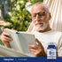 An older man comfortably reading a book in a hammock next to a B-12 bottle, enjoying a relaxing lifestyle moment.