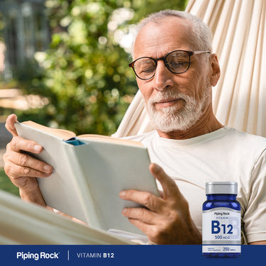 An older man comfortably reading a book in a hammock next to a B-12 bottle, enjoying a relaxing lifestyle moment.