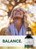 Lifestyle image of smiling woman outdoors with Carlyle Liquid Sea Moss bottle and graphic stating BALANCE.