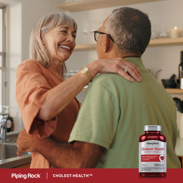 An older couple hugging in their kitchen, with a Cholest-Health bottle prominently on the counter.