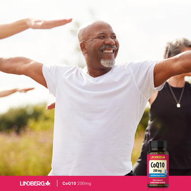 A senior Black man practicing yoga outside with a CoQ10 supplement bottle nearby.