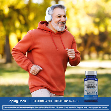 An older man is jogging outdoors with a bottle of Electrolytes Hydration Tablets nearby.