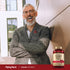 Older man laughing against a wall with a Guggul Extract bottle beside him.