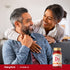 A happy couple sitting on a couch, smiling and holding D3 Softgels.