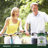 A middle-aged couple cycling outdoors with a bottle of Holy Basil, promoting an active lifestyle and wellness.