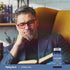 A man with grey hair and glasses is reading a book next to a Lutein + Zeaxanthin supplement bottle.