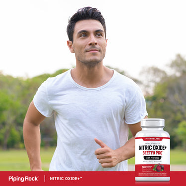 A young man jogging outdoors gives a thumbs up while holding a Nitric Oxide BeetFit Pro bottle.