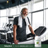 Adult smiling while standing on a treadmill at a gym, with a Piping Rock Organic Moringa Leaf Powder bottle nearby