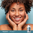 Smiling adult with hands resting on face and Piping Rock Collagen + C supplement bottle nearby