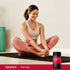 A young woman stretches on a yoga mat next to a Beet Root bottle, reflecting a healthy lifestyle scene.