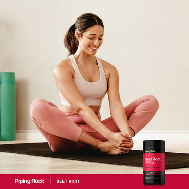 A young woman stretches on a yoga mat next to a Beet Root bottle, reflecting a healthy lifestyle scene.