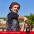 Smiling young man stretches his arm beside a Pre-Workout Intensifier, looking at the camera.