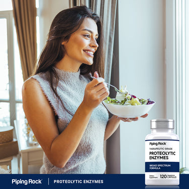 A woman enjoys a salad beside a bottle of Proteolytic Enzymes, using a fork to eat.