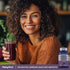 Young woman smiling with a smoothie beside a bottle of Resveratrol Berberine Grape Seed Quercetin Complex.