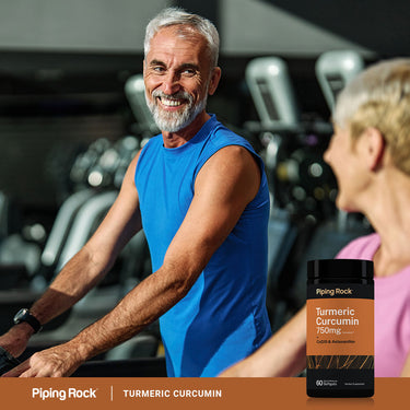 An older man and woman exercising in a gym with a Curcumin + CoQ10 Astaxant bottle nearby.