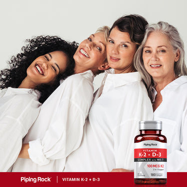 Four smiling women pose with a bottle of Vitamin K-2 + D-3, showcasing friendship and wellness.