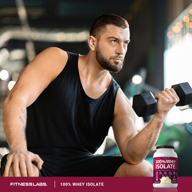 A young man works out with a dumbbell next to a tub of 100% Whey Isolate.