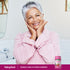 Senior woman smiling while holding a bottle of Women's Multivitamin Gummies in a lifestyle setting.