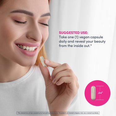 A young woman smiling while holding a single Hyaluronic Acid capsule.