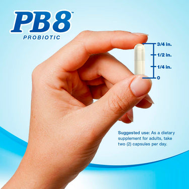 A hand holding a PB8 Probiotic capsule, measuring 3/4 inch in length.