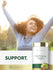 Young woman outdoors smiling with raised arms next to a Triphala bottle.