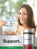 Young woman smiling while eating cereal with a Horbäach Cranberry supplement bottle beside her.