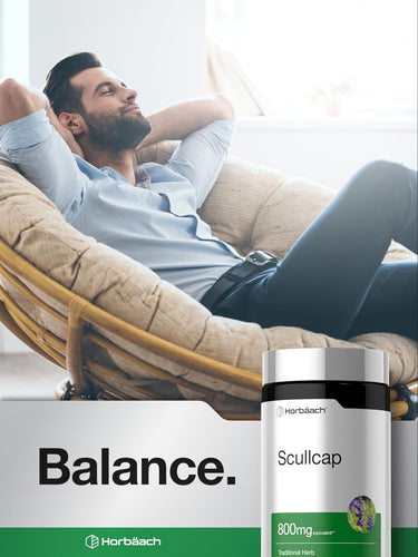 Adult man relaxes in a rattan chair with eyes closed, holding a Horbäach Scullcap supplement bottle.
