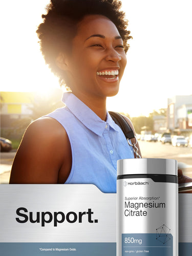 Young African American woman smiling in sunlight with a Horbaach Magnesium Citrate bottle outdoors.