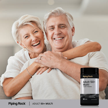 An older couple hugging and laughing on a couch, next to a bottle of Adult 50+ Multi vitamins.