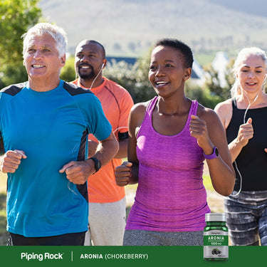 Four diverse adults running outdoors with a bottle of Aronia, also known as Chokeberry.