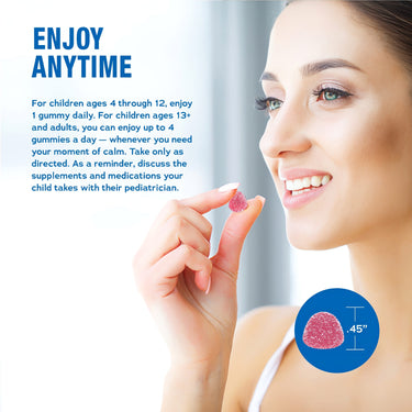 An adult woman smiles while holding a Calm Raspberry Lemon gummy.