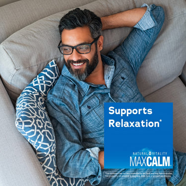 A middle-aged man relaxes on a couch, smiling with a Natural Vitality MAXCALM product overlay stating 'Supports Relaxation*'.