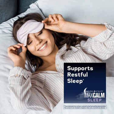 Young woman smiling in bed holding a sleep mask, suggesting restful sleep with NV Sleep Gummies.