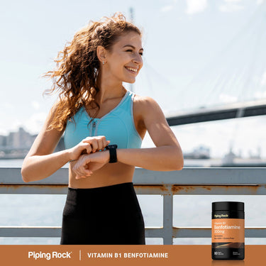 Woman in athletic wear checking her smartwatch outdoors with Piping Rock Vitamin B1 Benfotiamine 300mg bottle nearby