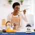 Lifestyle image of adult cooking in kitchen with Piping Rock Vitamin B100 B-Complex supplement bottle nearby