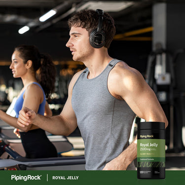 Lifestyle image of two adults exercising on treadmills at a gym with a Piping Rock Royal Jelly 2500 mg supplement bottle displayed in the bottom right corner