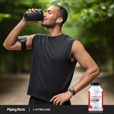 A young man drinks from a water bottle near an L-Citrulline bottle.