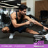 A young man stretches in a gym beside a jar of Glutamine Powder.