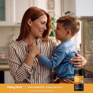 A smiling woman holds a young boy with a bottle of Kids Probiotic Chewables in view.