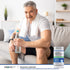 Adult man seated on a sofa holding a bottle of water with Advanced Prostafit Prostate Support supplement bottle nearby