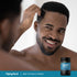 A young man examines his hair in a mirror beside a DHT Hair Formula bottle.