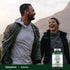 Adults laughing while walking outdoors, holding a bottle of Moringa.