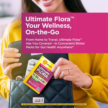 A young woman smiles as she places an Ultimate Flora Probiotic Go Pack into her black handbag.