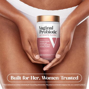 Adult woman holding a RenewLife Vaginal Probiotic bottle in cupped hands in front of her lower abdomen, wearing white underwear.