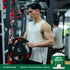 Young adult male exercising with a 20 KG weight plate in a gym, next to a tub of WheyFit Isolate protein.