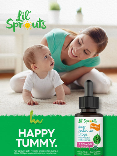 Mother smiles while playing with baby on the floor near a bottle of Lil' Sprouts Baby Probiotic Drops.
